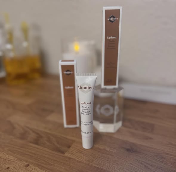 AlumierMD LipBoost and skincare products on a wooden surface